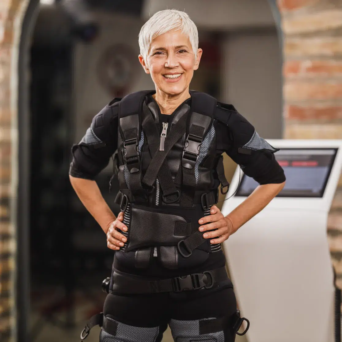 Senior woman smiling in a fitness gym, wearing suit.