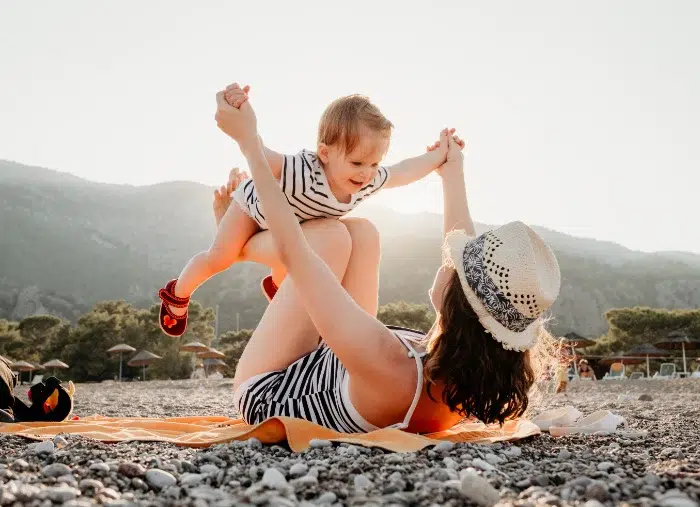 A woman and a child playing on a sunny beach.