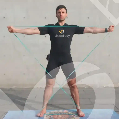 A person in a black "visionbody" suit performs an exercise with resistance bands, standing on a mat with arms extended horizontally and legs spread apart.